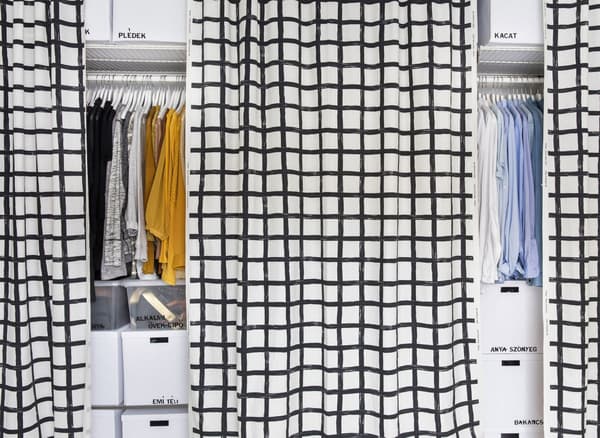 Bedroom storage and clothing behind black and white curtains.