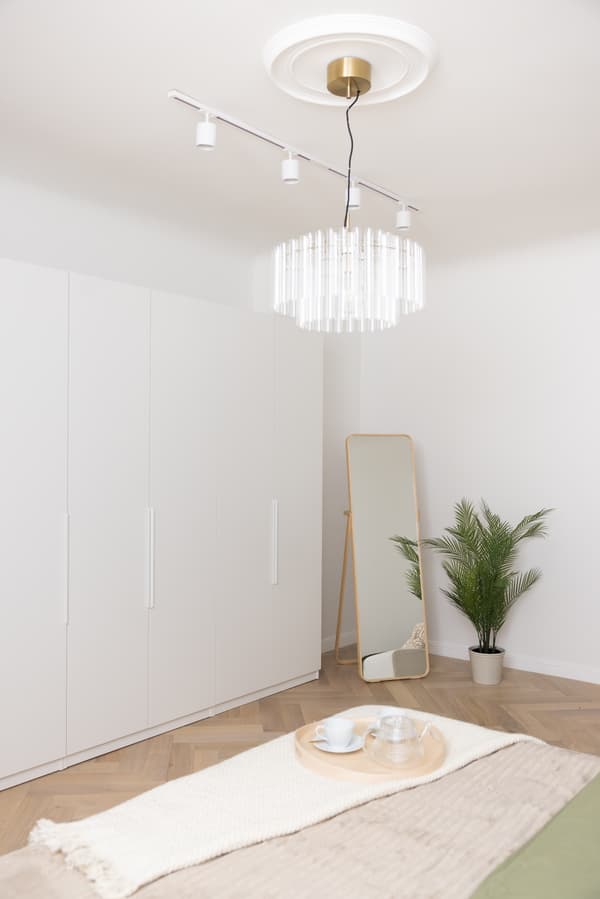 Bedroom with a bed, ceiling lamp and a white wardrobe along the wall.