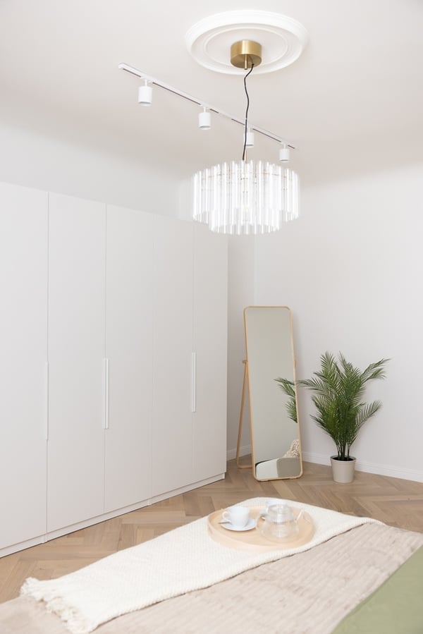 Bedroom with a bed, ceiling lamp and a white wardrobe along the wall.