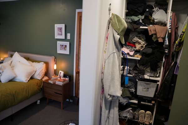 Bedroom with bed and wardrobe full of clothes.
