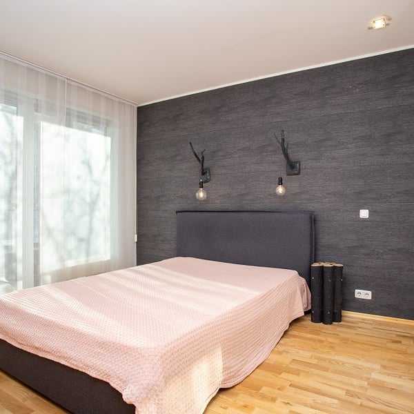 Bedroom with dark accent wall, upholstered bed, and soft pink bedding.