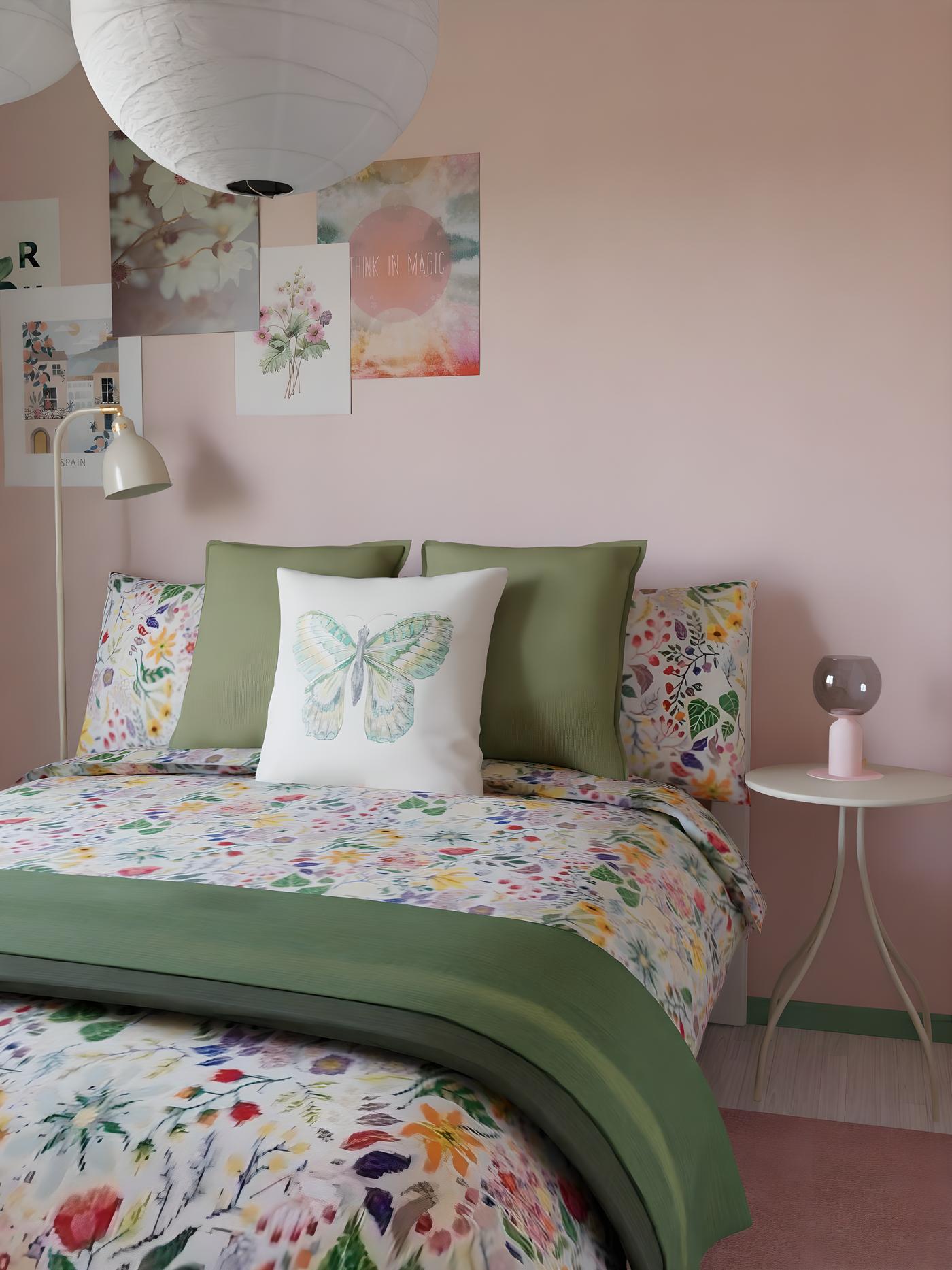 Bedroom with pastel pink walls and a bed covered in green floral textiles.
