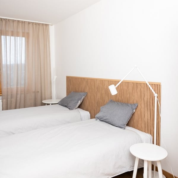 Bedroom with wooden slat headboard, white bedding, and bedside tables with reading lamps.