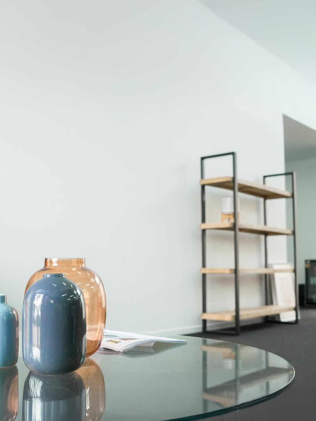 Before image of space with glass table and shelves.