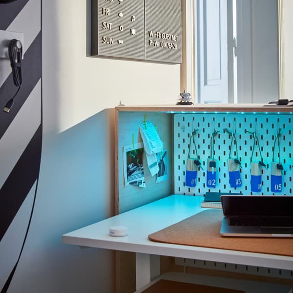 Behind the reception desk, a height adjustable desk, a wall of keys to different rooms, a laptop and some sticky notes.