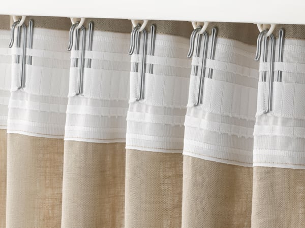 Beige curtain hangs with finger hooks on VIDGA curtain rail.