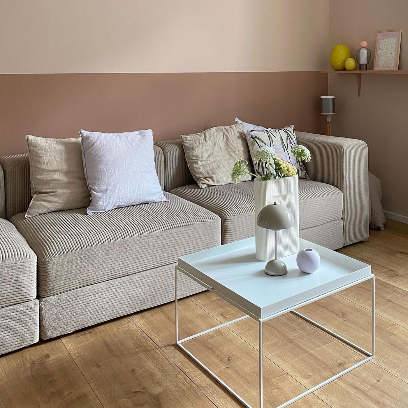 Beige manchestersoffa i rum med puderrosa väggar.