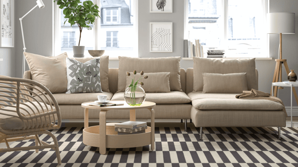Beige SÖDERHAMN modular sofa in bright living room with striped rug, light wood coffee tables, and decorative cushions.