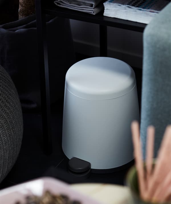 Berbentuk kon dengan penjuru membulat, tong berpedal SNÄPP diletakkan separa di bawah meja antara sofa dengan bangku berkusyen di ruang tamu.