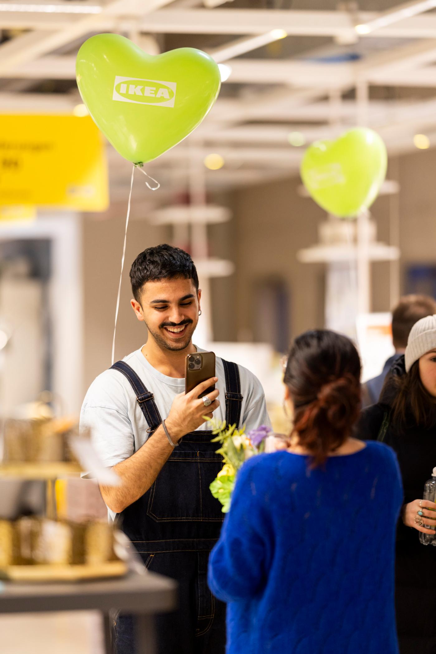 Besucher fotografiert einen besonderen Moment bei der Ampelparty mit grünen Herzluftballons im Einrichtungshaus.
