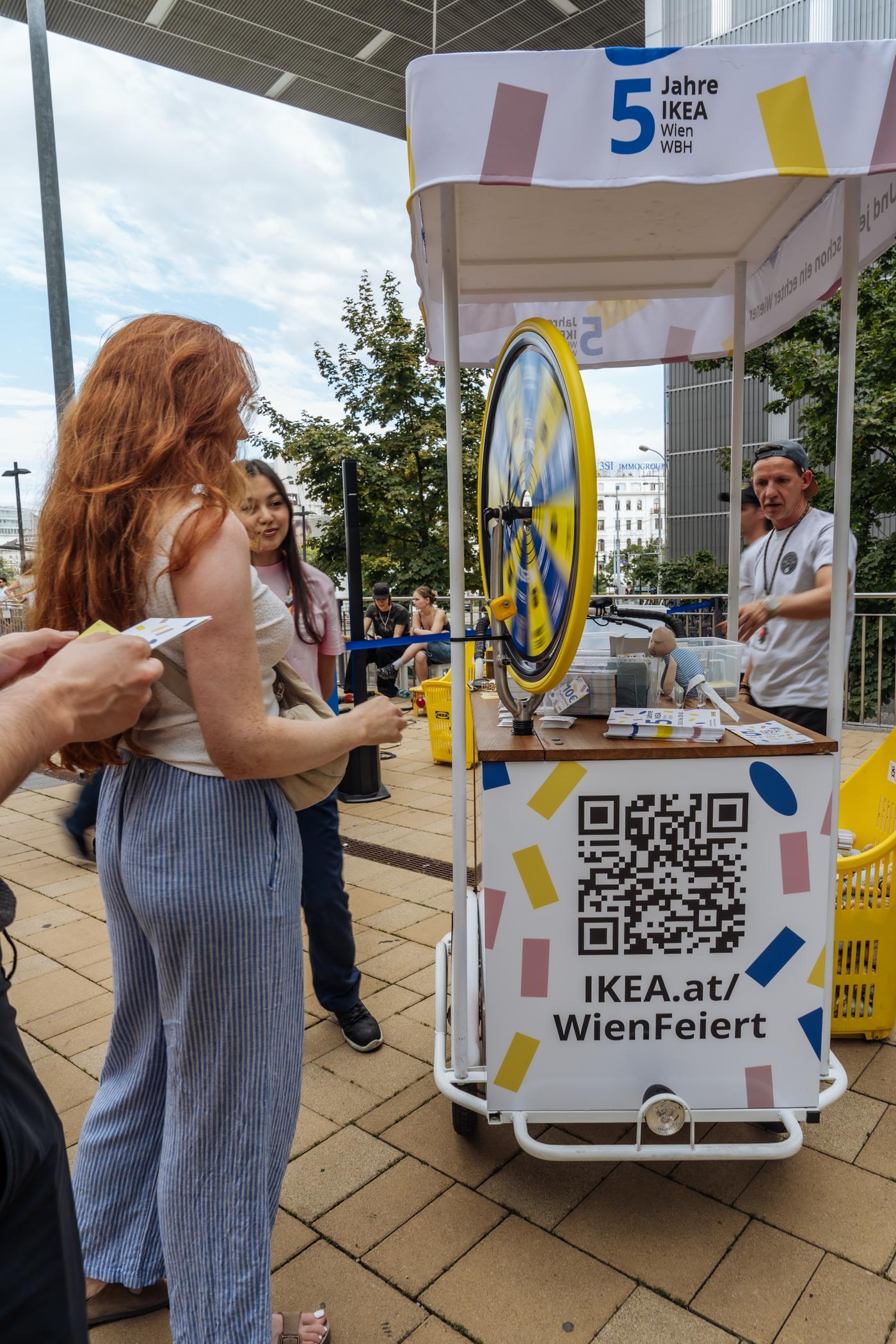 Besucherinnen drehen am Glücksrad beim 5-jährigen Jubiläum von IKEA Wien Westbahnhof.