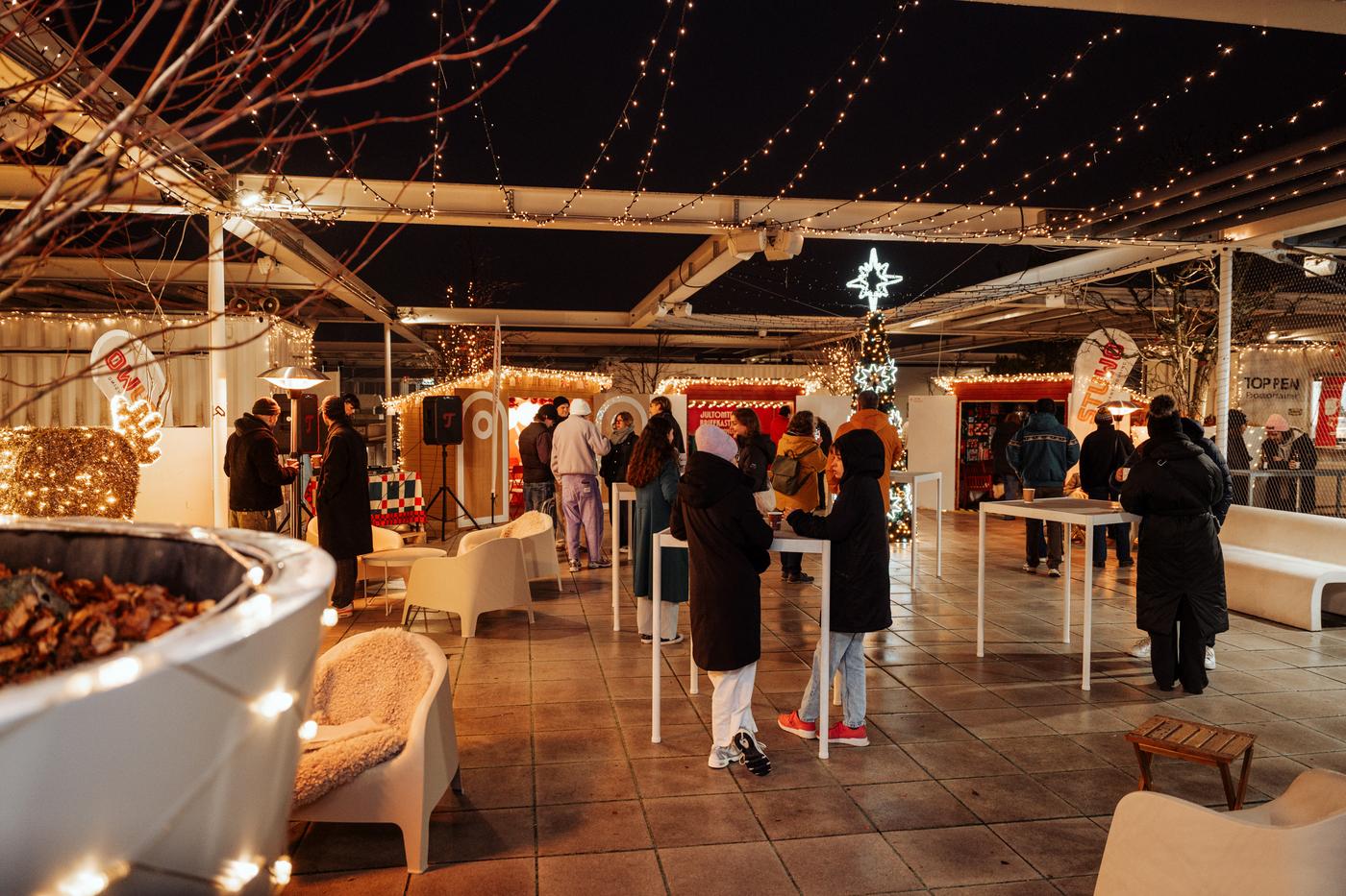 Besucherinnen und Besucher genießen einen stimmungsvoll beleuchteten Husmas Weihnachtsmarkt auf der Rooftop-Terrasse von IKEA Wien Westbahnhof.