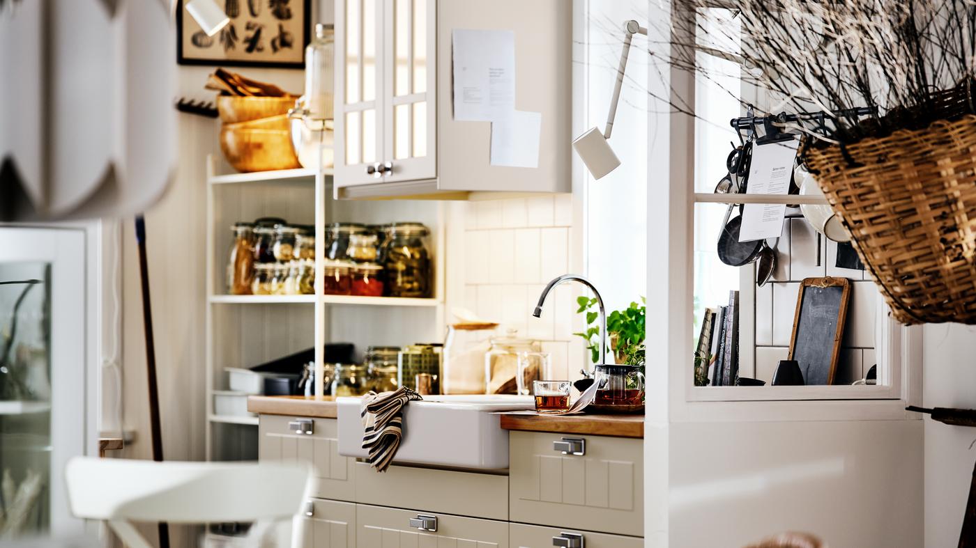 Béžová tradičná kuchyňa so skrinkami METOD, na nich dvierka a čelá zásuviek STENSUND, biely drez a polica s dózami a kuchynským náčiním.