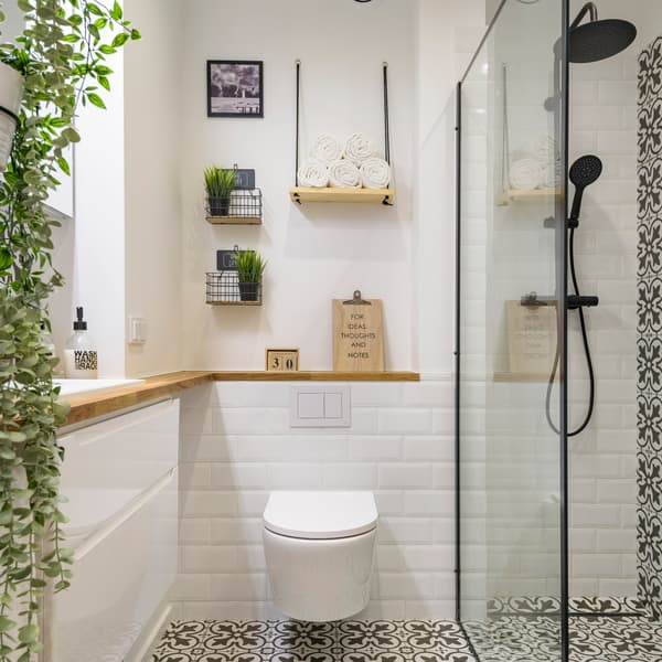 Biała łazienka z drewnianym blatem i dużą ilością roślin.