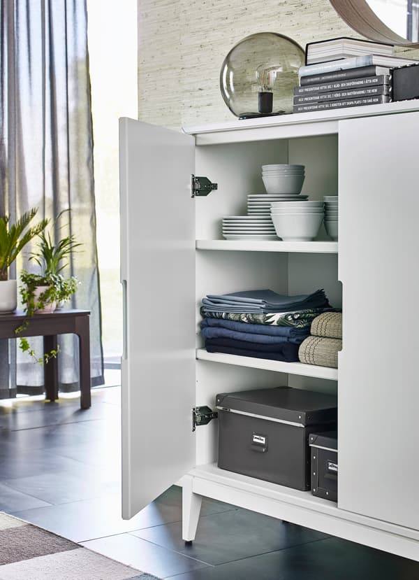 Biała szafka IKEA REGISSÖR to mała, zamykana szafka do przechowywania z trzema półkami, która w każdym pokoju pomieści dodatkowe talerze i dekoracje.