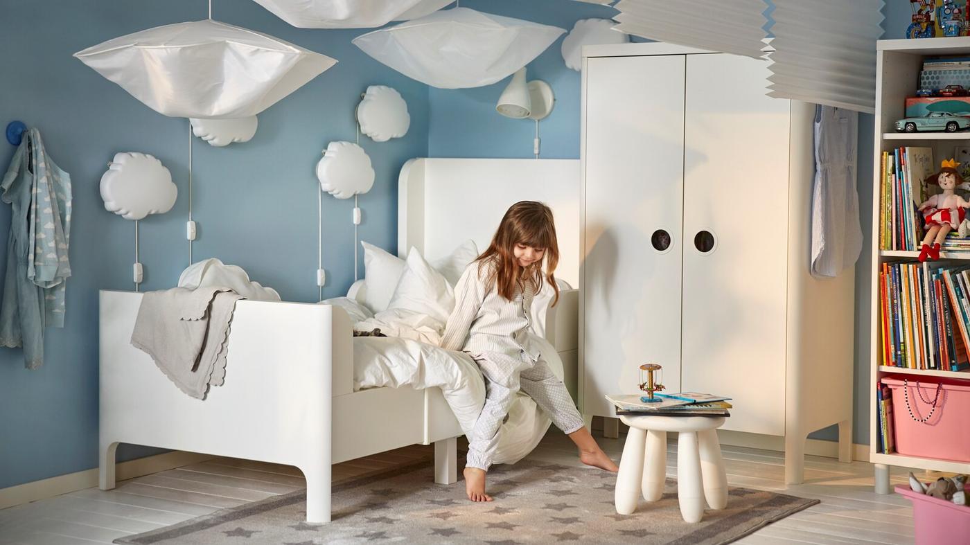 biało-niebieski pokój dziecięcy z dziewczynką na łóżku