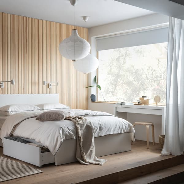 Biały stół jadalniany z białymi krzesłami przy kuchni z białymi frontami.