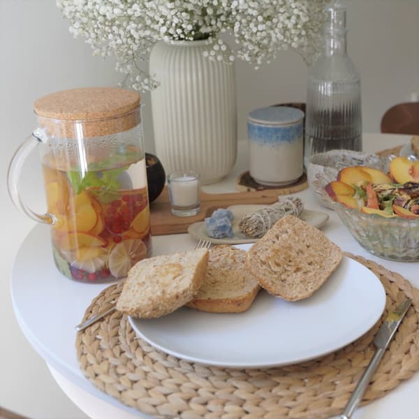 Biały talerz z pieczywem stojący na stole z podkładkami z liści bananowca.