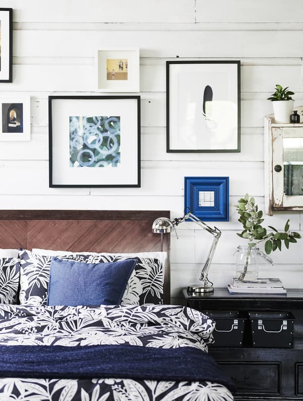 Biancheria da letto bianca e blu e quadri alla parete.