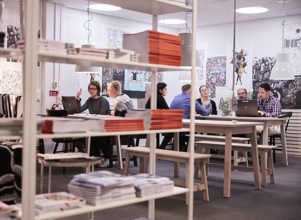 Bibliothèques, art mural et personnes travaillant en groupe à de longues tables.