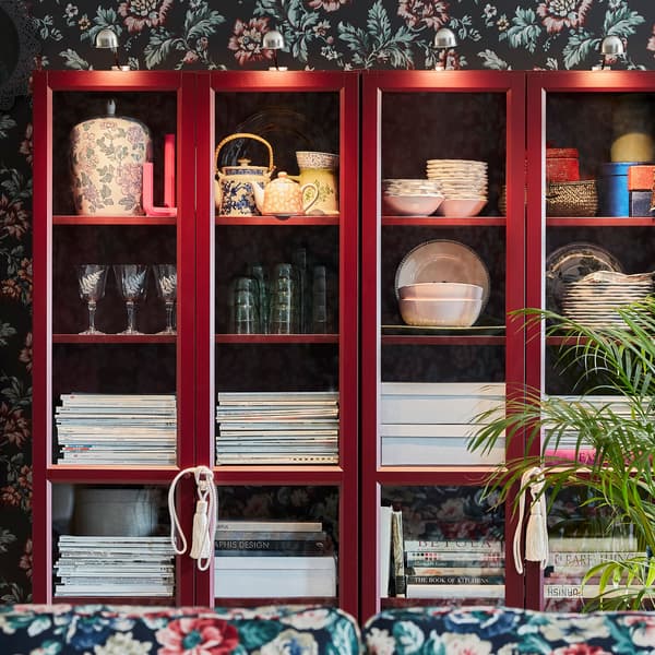 Bibliothèques IKEA BILLY rouge foncé, pour ranger des papiers, des magazines et différents objets derrière les portes vitrées.