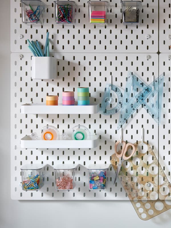 Biela dierkovaná doska SKÅDIS s bielymi policami a transparentnými úložnými dielmi.