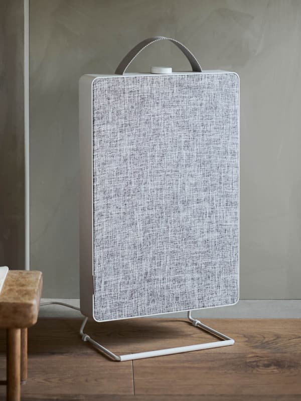 Bielo-sivá čistička vzduchu FÖRNUFTIG stojí na drevenej podlahe.