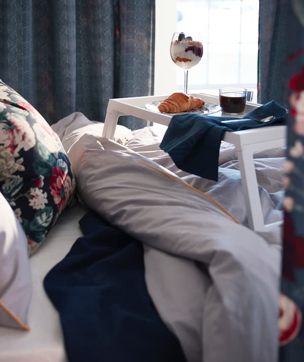 Biely podnos IKEA KLIPSK s luxusnými raňajkami položený na posteli.