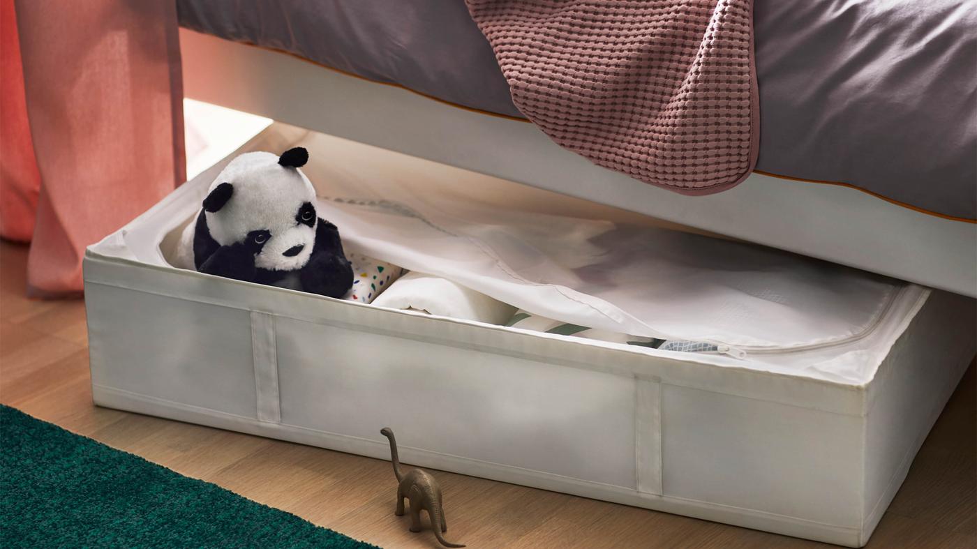 Biely úložný diel SKUBB pod bielou posteľou.