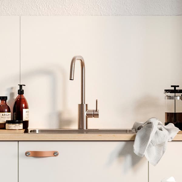 Bijela zidna ploča, bijela kuhinjska fronta s kožnim ručkama ispod sudopera, kafeterija i sapun nalik onome u apoteci.