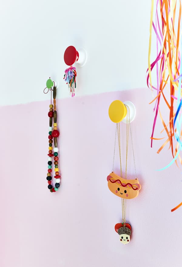 Bijoux accrochés à des patères colorées.