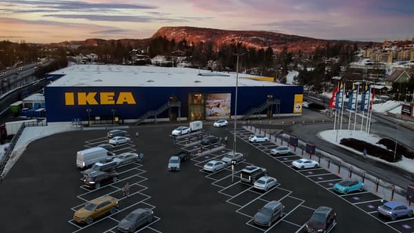 Bilar står på parkering utanför ett IKEA-varuhus varav några laddar
