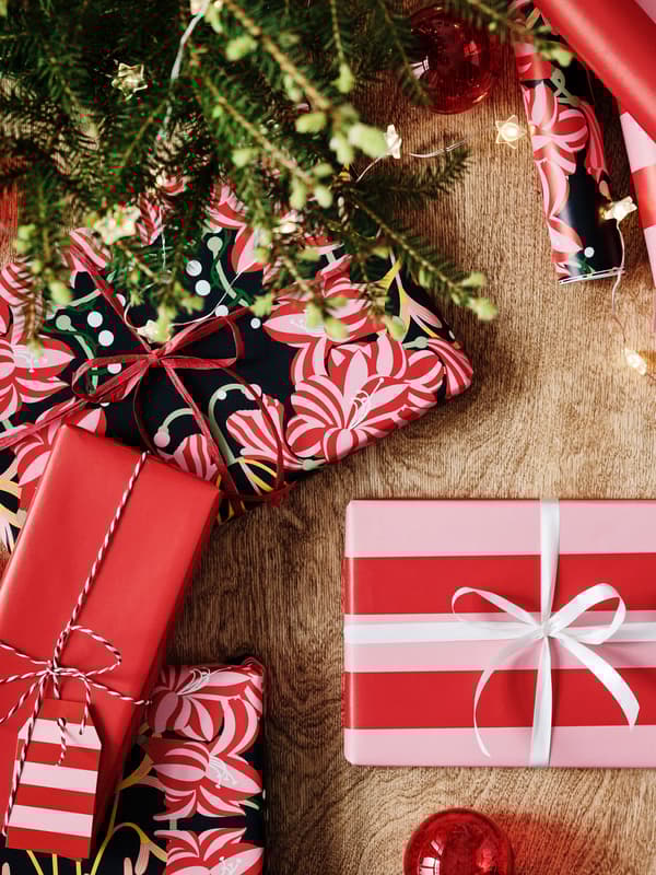 Bild tagen uppifrån på julklappar som är inslagna i presentpapper i röda och rosa nyanser.
