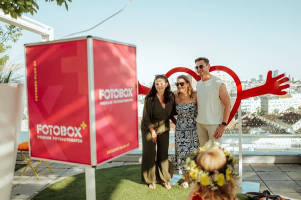 Bild zeigt Personen die gerade ein Foto bei der Fotobox vor einem Herzaufsteller machen.