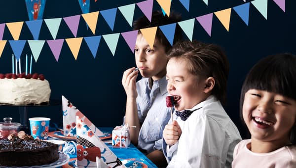 Bilde av glade barn som skal feire bursdag med kake på bordet.