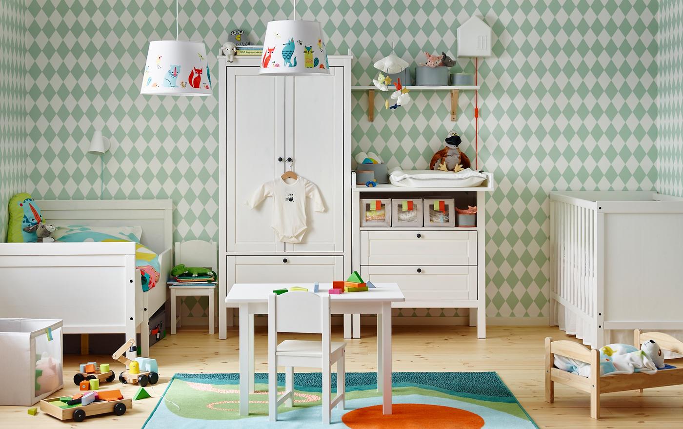 Bilik kanak-kanak yang dikongsi ini dilengkapi meja tukar lampin SUNDVIK yang ditukar menjadi almari berlaci, katil bayi SUNDVIK dan katil boleh dipanjangkan SUNDVIK disandarkan di dinding belakang dengan kertas dinding bercorak badut hijau putih.