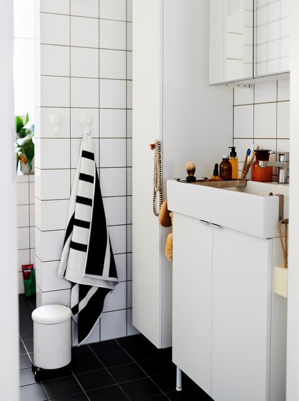 Bilik mandi berjubin putih yang dilengkapi dengan kabinet dan sink cuci tangan LILLÅNGEN berwarna putih, dan bertaburan dengan hiasan dan aksesori.