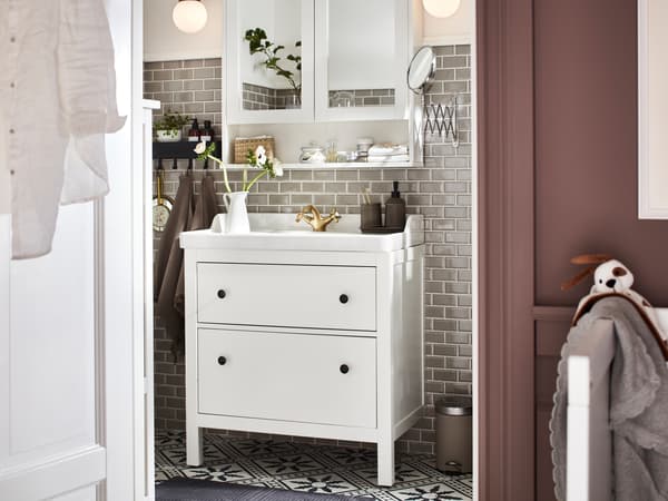 Bilik mandi yang mempunyai kabinet bawah sink dengan dua laci HEMNES/RÄTTVIKEN berwarna putih dan kabinet bercermin dua pintu HEMNES berwarna putih.