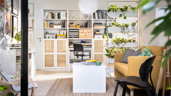 BILLY bookcases against a wall behind a MITTZON frame with castors, an ÖSTAVALL adjustable coffee table and a PÄRUP sofa.