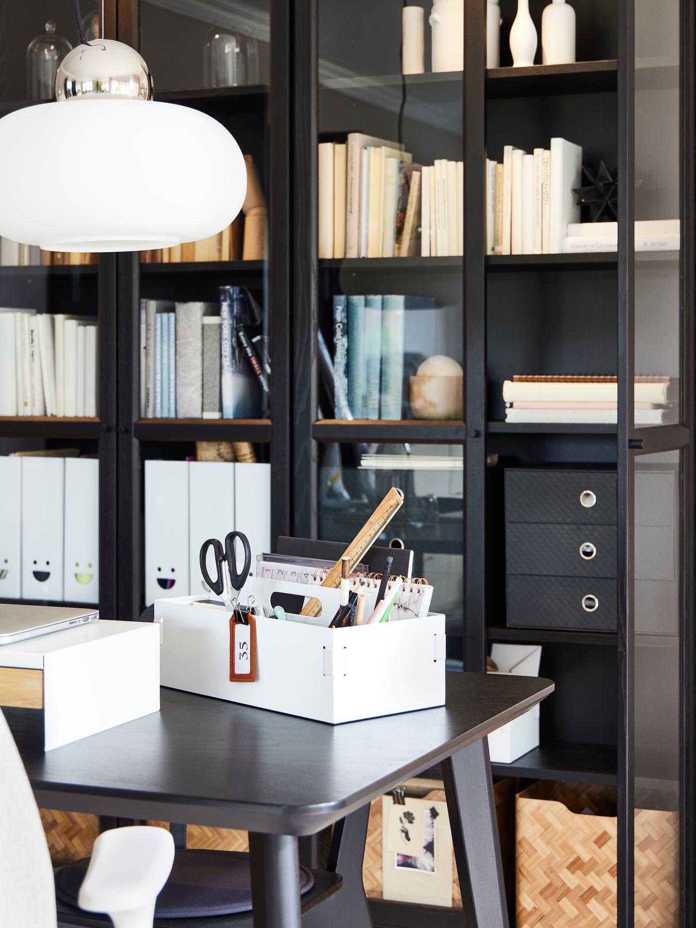 BILLY bookcases in black-brown fitted with OXBERG doors in black-brown. The shelves contain books, boxes and magazine files.