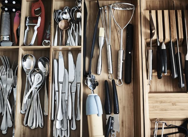 Bird's-eye view of cutlery sorted in kitchen drawer inserts.