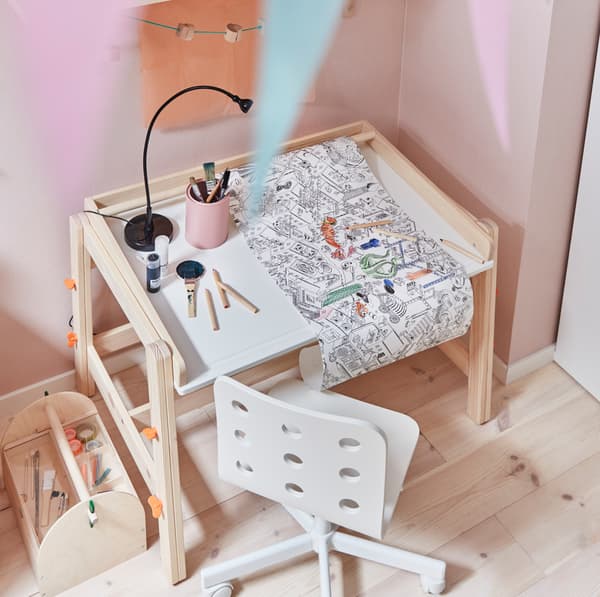 Biroul pentru copii FLISTAT, din pin, de la IKEA, pe care se află creioane colorate și schițe.