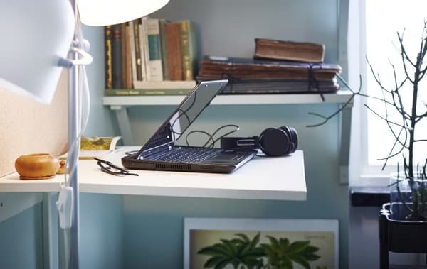 biurko mocowane do ściany z laptopem i lampą