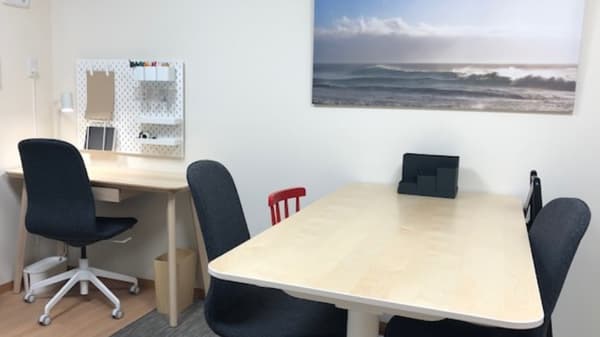 ベージュのデスクに濃紺のオフィスチェアが並んでいる。