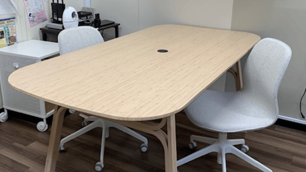 ベージュの長机にグレーのオフィスチェアが2脚並んでいる。