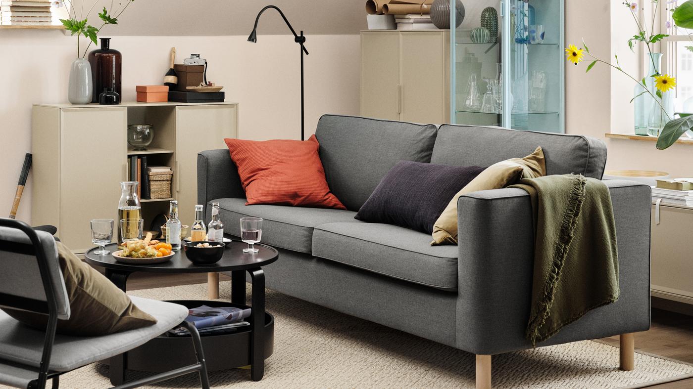 ベージュ系のリビングリームに、グレーのPÄRUP/ペルプ ソファとクッション3個。 その前に、ドリンクとスナックが載ったコーヒーテーブル。