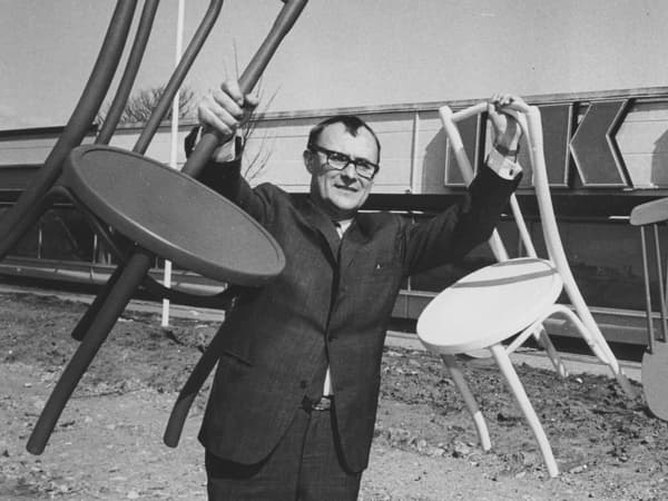 Black and white photo of Ingvar Kamprad holding up two chairs
