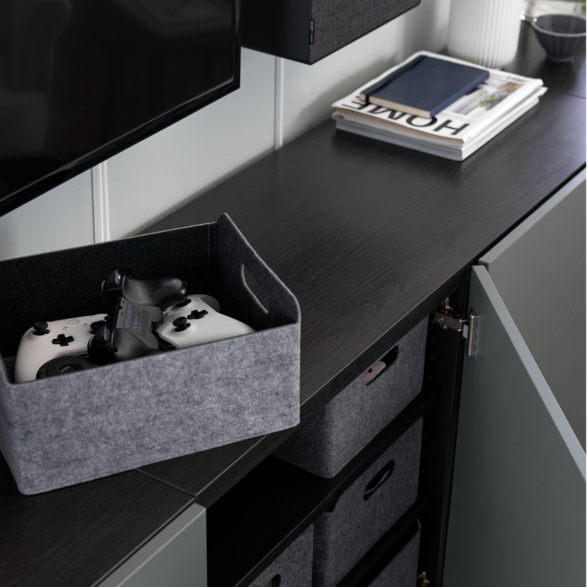 Black BESTÅ cabinet with an open door with grey storage boxes.