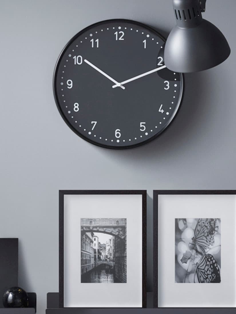 Black clock and frames on wall shelf