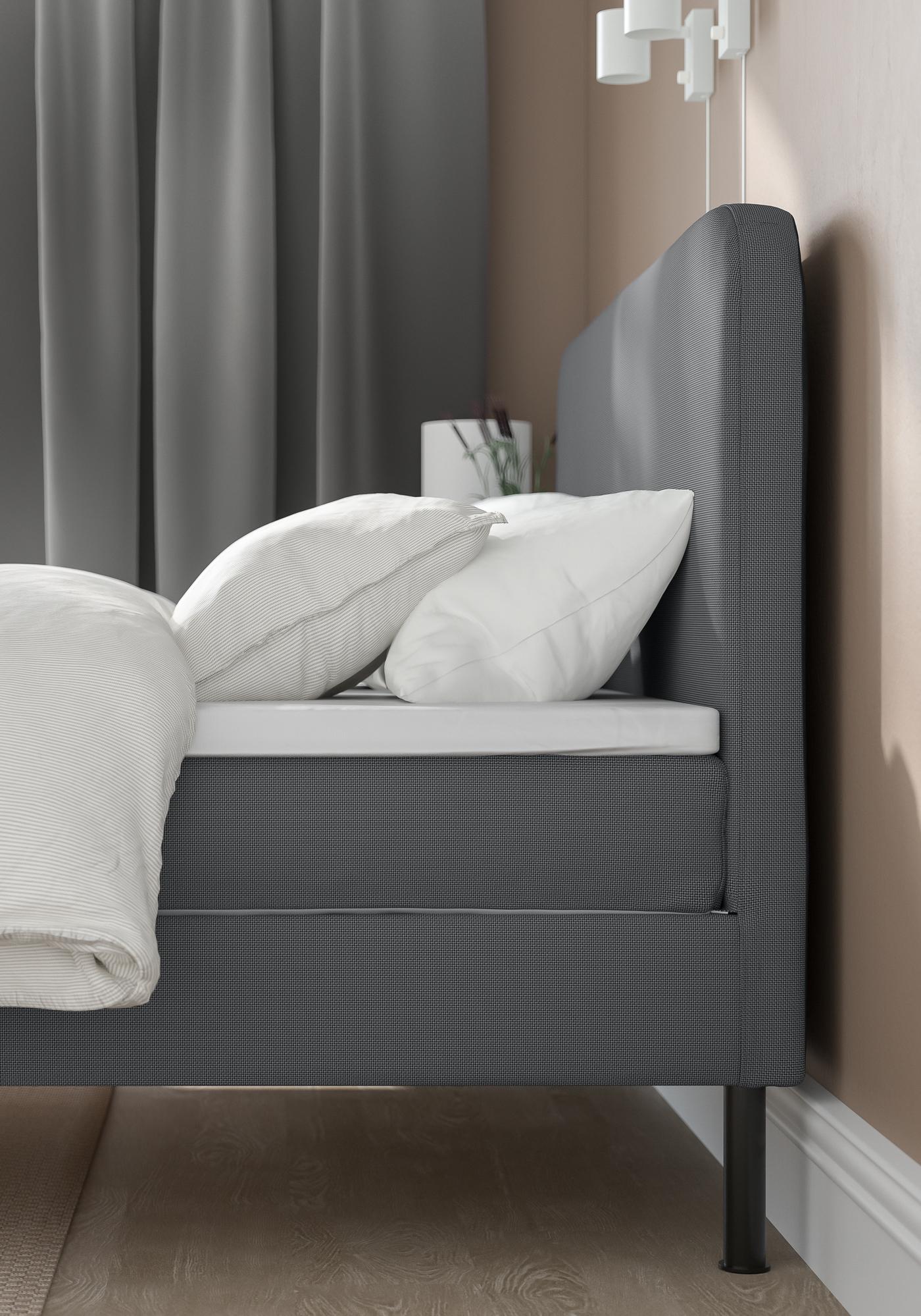 BLÅFJÄLLET seng i mørkegrå står op ad en beige malet væg i et soveværelse